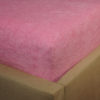 Prześcieradło frotte z gumką jasno różowe na rogu łóżka firmy TuliSen.
