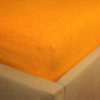 Prześcieradło frotte z gumką w zgaszonej pomarańczy na rogu łóżka firmy TuliSen.