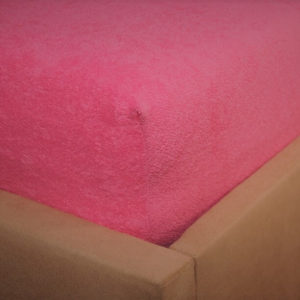 Prześcieradło frotte z gumką różowe na rogu łóżka firmy TuliSen.