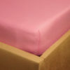 Prześcieradło jersey z gumką jasno różowe na rogu łóżka firmy TuliSen.